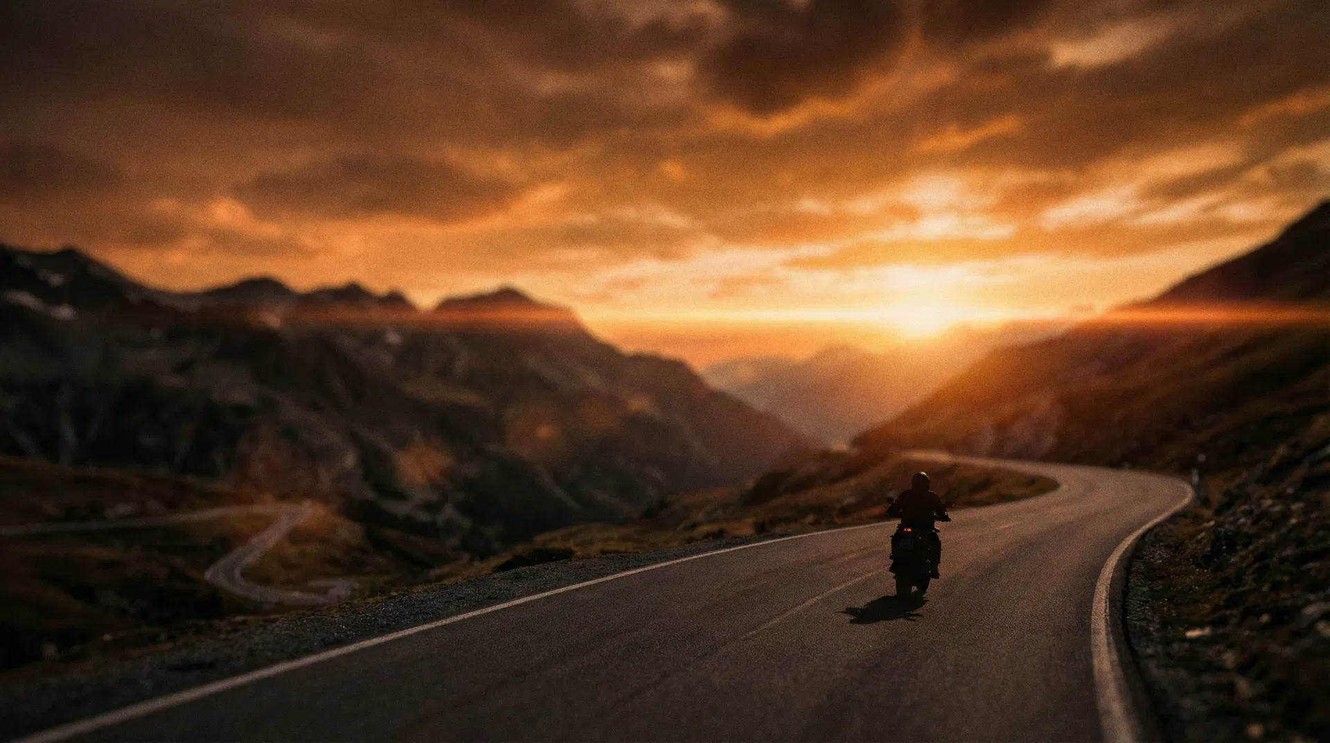 Motorradfahrer bei Sonnenuntergang auf einer Bergstraße